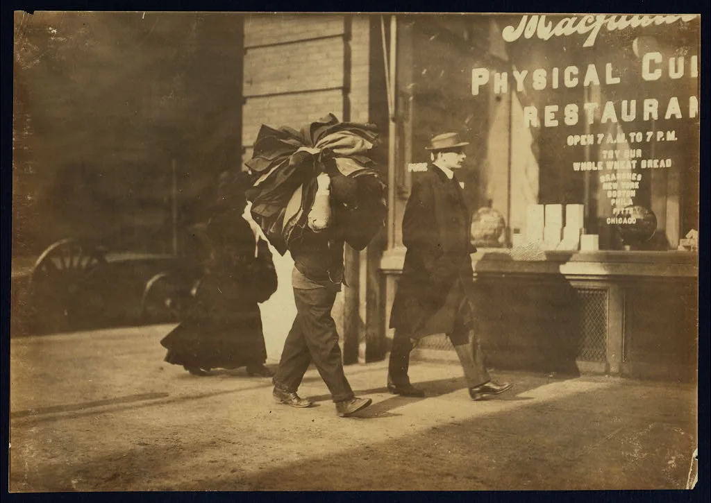 Man carrying bundle of garments. Bleecker St., N.Y. Location: New…, New York (State), 1912